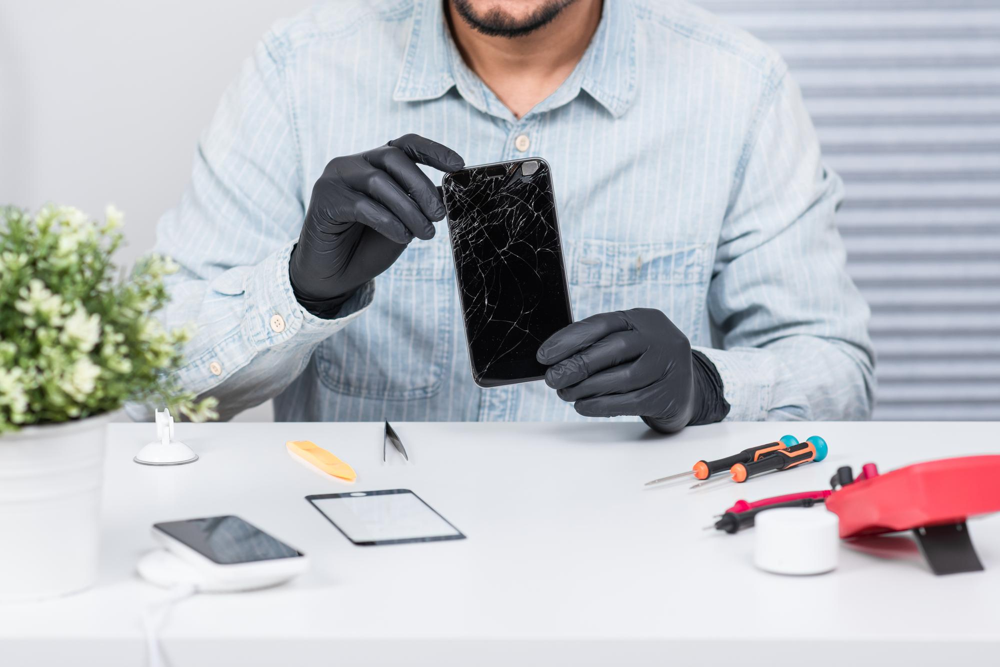 iPhone 15 reparatie Dokkum &mdash; iPhone scherm reparatie Dokkum specialist met beschermhandschoenen werkt aan iPhone